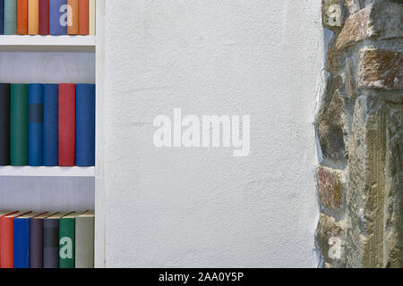 Bunte Bücherregal in weißen Wand neben der Mauer aus Stein Stockfoto