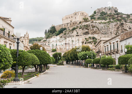 SCICLI, ITALIEN - OKTOBER 3, 2019: Straße mit Pflastersteinen auf der Straße in der Nähe der alten Kirche und Gebäuden in Scicli Stockfoto