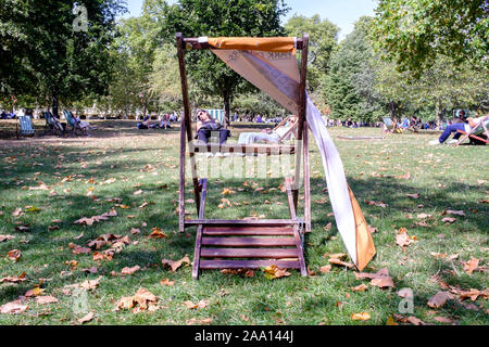 Menschen entspannend auf Liegestühlen in der St. James's Park, London, UK Stockfoto