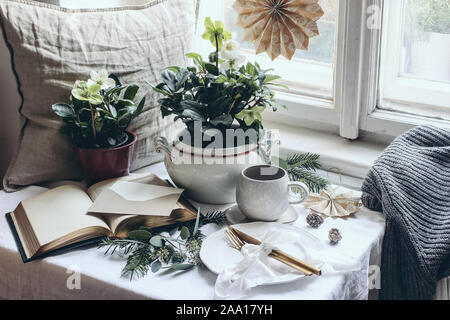 Moody winter Frühstück noch leben Szene. Weihnachten festlich gedeckten Tisch mit goldenem Besteck, Tasse Kaffee, Grußkarte, Eukalyptus und Tanne br Stockfoto