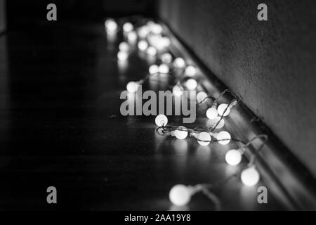 Schwarze und weiße Stimmung und Ton in der Nähe zu sehen, der dekorativen Kabel led Kleine warm-weißes Licht Lampen auf dem Boden lag an der Ecke Dunkel und Dunkel. Stockfoto