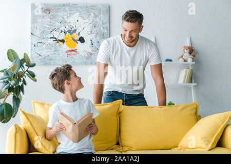 Gerne Vater steht in der Nähe von Son Buch beim Sitzen auf dem Sofa Stockfoto