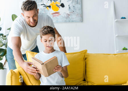 Gerne Vater steht in der Nähe von Son mit Buch Stockfoto