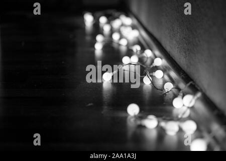 Schwarze und weiße Stimmung und Ton in der Nähe zu sehen, der dekorativen Kabel led Kleine warm-weißes Licht Lampen auf dem Boden lag an der Ecke Dunkel und Dunkel. Stockfoto