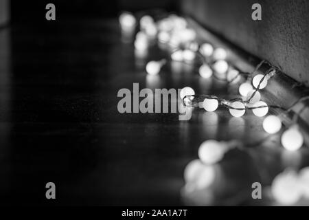 Schwarze und weiße Stimmung und Ton in der Nähe zu sehen, der dekorativen Kabel led Kleine warm-weißes Licht Lampen auf dem Boden lag an der Ecke Dunkel und Dunkel. Stockfoto