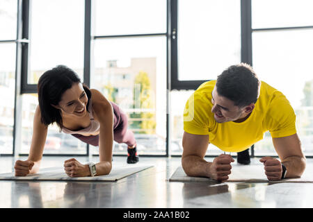 Lächelnd Sportler und Sportlerin, Plank auf Fitness Matten im Sportzentrum Stockfoto