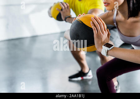 Blick auf Sportler und Sportlerin tun Hocke mit Kugeln im Sportzentrum 7/8 Stockfoto