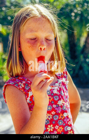 Eine 7-jährige Mädchen saugt ein Popsicle an einem heissen Sommertag in einem Laguna Niguel, CA, Park. MODEL RELEASE Stockfoto