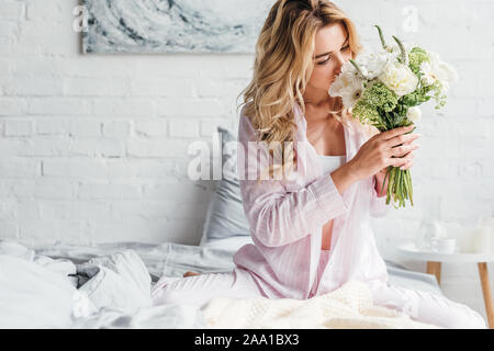 Junge Frau mit Gesicht, während duftende Blumen im Schlafzimmer Stockfoto