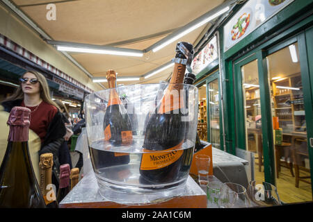 Wien, ÖSTERREICH - NOVEMBER 6, 2019: Prosecco Flaschen auf dem Display in einem Eiskübel in einer Wiener Markt mit Menschen die Verkostung der Wein hinter sich. Prosecco ist ein Stockfoto