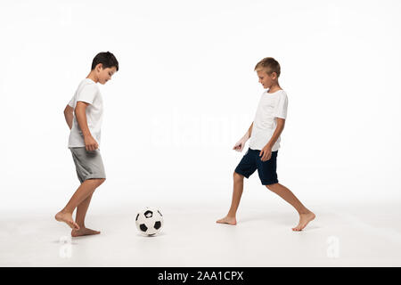 Zwei Brüder im Schlafanzug Fußball spielen auf weißem Hintergrund Stockfoto