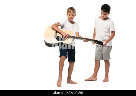 Junge in der Nähe von Bruder spielen akustische Gitarre auf weißem Hintergrund Stockfoto