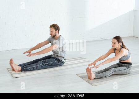 Junger Mann und Frau praktizieren von Yoga im Sitzen nach vorne beugen darstellen Stockfoto