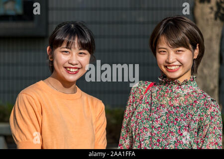 Porträt von zwei japanischen jungen Frauen lächeln suchen Kamera, nihonjin Ethnizität, draußen in Kanawawa, Japan Stockfoto