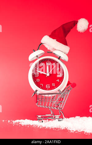 Weihnachten Santa Hut auf rote Uhr, im Warenkorb ausgeglichen. Last Minute Weihnachten shopping Konzept mit Leeren leeren Raum für Text. Stockfoto