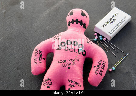 Rosa Voodoo Puppe mit einem Bücher von Voodoo Pins und Nadeln Stockfoto