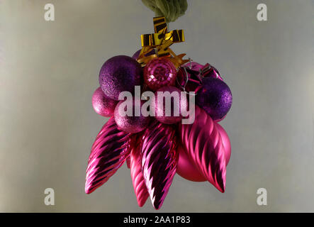 Weihnachtsschmuck in den Farben lila mit einem goldenen Stern hängen von einem grünen Band Stockfoto