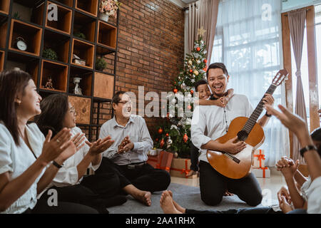 Familie Gitarre spielen während der Heiligabend Stockfoto