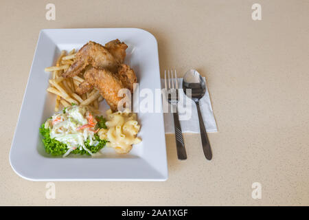 Close-up detaillierte Ansicht von zwei Stücke der Fried Chicken Wings, Pommes frites, Mac & Käse und frischen Krautsalat auf grünem Salat Stockfoto