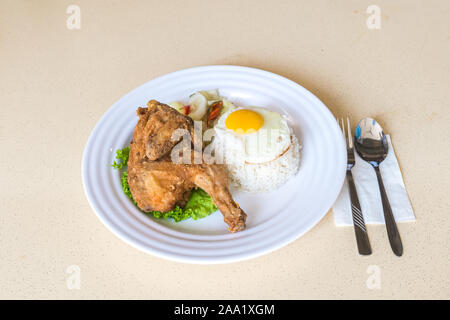 Fried Chicken Sache auf Kopfsalat mit abgeholt Gemüse, Sonnenseite, Spiegelei, und Thai White Jasmin Reis. Essen auf dem Tisch. Stockfoto