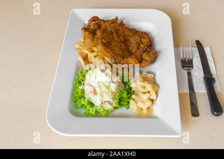 Gebratene Brotkrumen Hühnerschnitzel mit Mac & Käse, Krautsalat auf grünem Salat Stockfoto