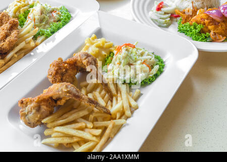 Close-up detaillierte Ansicht von zwei Stücke der Fried Chicken Wings, Pommes frites, Mac & Käse und frischen Krautsalat auf grünem Salat Stockfoto