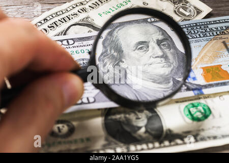 Konzept zum Thema Kontrollieren, ob das Geld für die Authentizität. Benjamin Franklin schaut durch ein Vergrößerungsglas in den Rahmen. Kontrolle der Dollar Stockfoto