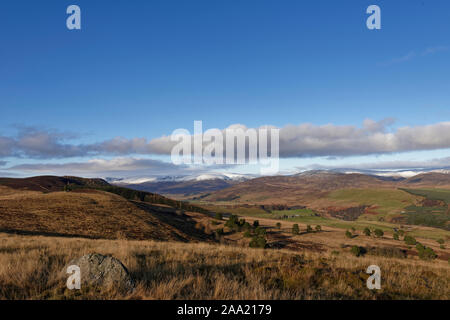 Siedlungen und Felder im Tal von Glen Clova, von tulloch Hügel gesehen, hoch oben in den Angus Glens, und nach Norden zu den verschneiten Cairngorms. Stockfoto