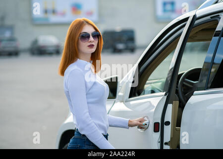 Yong hübsche Frau, die in der Nähe von einem großen all terrain Auto im Freien. Treiber Mädchen in legere Kleidung außerhalb Ihres Fahrzeugs. Stockfoto