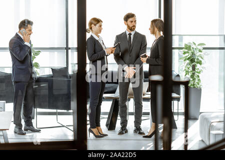 Angestellte von Finanzinstituten in einigen Unternehmen, stehen und sprechen in den Luxus Büro. Blick durch die Tür Stockfoto