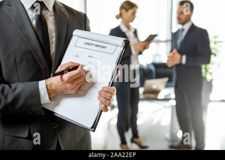 Mitarbeiter der Bank sowie einige statistische Meldung an die Bank Büro mit Kollegen auf dem Hintergrund, close-up Stockfoto