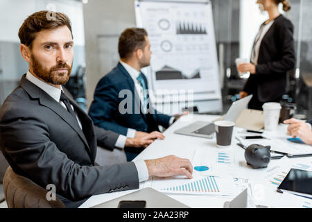 Porträt einer stattlichen Geschäftsmann während einer Konferenz mit Mitarbeitern im Konferenzraum sitzen Stockfoto