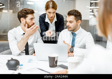 Team Leader helfen zwei männliche erschöpft, Mitarbeiter der Arbeit auf einem Laptop im Büro zu tun Stockfoto