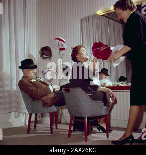 Sie versuchen, Hüte in den 1950er Jahren. Ein Paar sitzt vor einem Spiegel versuchen, Hüte auf. Er ist Humorist Erik Zetterström und sie ist Sickan Carlsson, Schauspielerin. Schweden 1950 Stockfoto