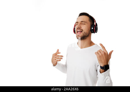 Hübscher junger Mann in Kopfhörer Musik hören und tanzen auf weißem Hintergrund. Stockfoto