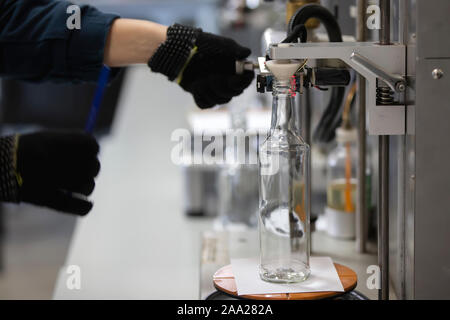 Glashütte. Hände halten eine Glasflasche über das Gerät. Die Kontrolle der Qualität von Glas Container Stockfoto