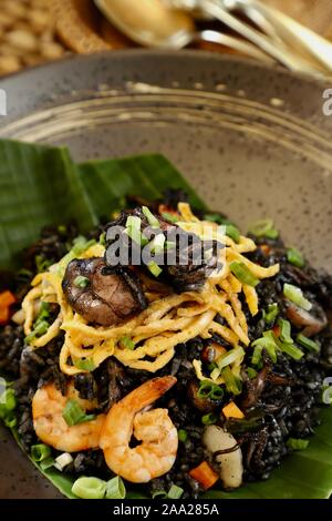 Nasi Goreng Cumi Hitam. Indonesische Reisgericht mit wokgemüse mit geschmorter Tintenfisch und seine in. Stockfoto