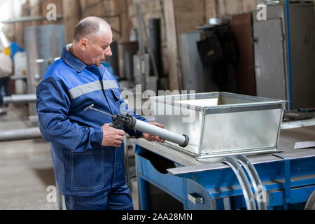 Belarus, Gomel, 25. April 2018. Fabrik für die Herstellung von Lüftungsrohren. Der Arbeiter in der Fabrik macht Lüftung Metallrohre Stockfoto