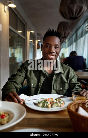 Junge afrikanische amerikanische Mann ist das Essen in einem Restaurant und genießen Sie leckeres Essen Stockfoto
