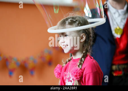 Belarus, Gomel Stadt, 10 April, 2016 Ferien für Kinder. Ein Kind in einer Seifenblase. Fröhliches Mädchen in der Show Stockfoto