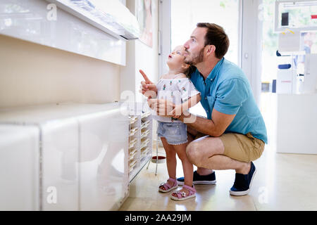 Gesundheit, Seh- und Vision Konzept. Kleines Mädchen Gläser mit Vater bei Optik store Stockfoto