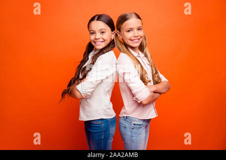 Portrait von positiven fröhliches Team von zwei süße Kinder Mädchen stehen Rücken an Rücken bereit lösen Schule Lösungen entscheiden, Entscheidungen tragen moderne Outfit isoliert Stockfoto