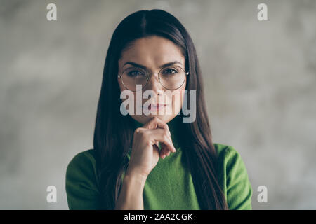 Nahaufnahme Foto von schweren zuversichtlich kluge Frau berühren Ihr Kinn mit der Hand Tragen einer Brille Brillen tragen isoliert Grau Farbe Wand Beton Stockfoto