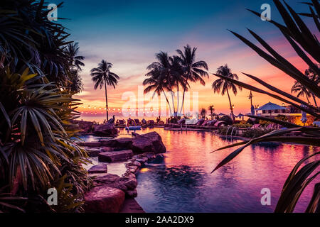 Atemberaubende Aussicht auf den Sonnenuntergang mit Palmen in Schwimmbad in Luxury Island Resort in Thailand widerspiegelt Stockfoto