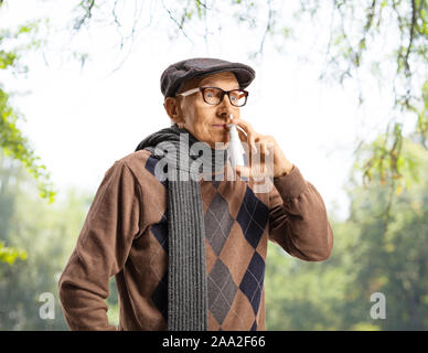 Ältere Menschen mit einem Nasenspray im Freien unter Bäumen Stockfoto