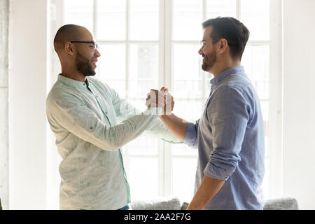 Mischlinge männliche Freunde in Brillen die Hände schütteln. Stockfoto
