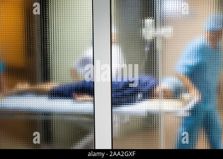 Weibliche Patienten, der von einer Gruppe von Ärzten in einem Krankenhaus OP-Saal auf einem gurney für Herzchirurgie transportiert Stockfoto