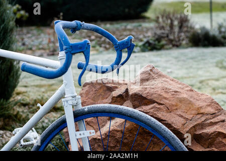 Teile von einem Fahrrad stehen im Garten wie Dekorationen, lackiert in Blau und Weiß Stockfoto