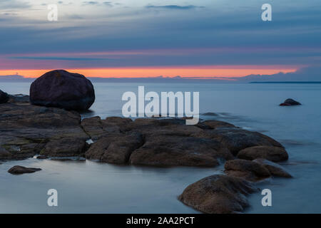 Sonnenuntergang Himmel über Steine und Flat Rock unter Ostsee sinkt. Fantastische Wildnis von Estland. Stockfoto