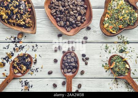 Interessantes Konzept mit einer Auswahl an Getränken. Kaffeebohnen, Obst, Tee und Kräuter auf einem Holztisch. Stockfoto